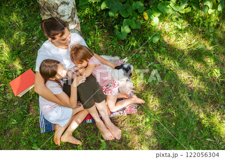 Overhead view of a mother hugging her daughters and dog in a garden 122056304