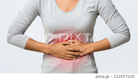 Close up of young african woman touching her belly, suffering from menstrual abdomen cramps, grey background Close up of young african woman touching her belly, suffering from menstrual abdomen cramps, grey background 122057220