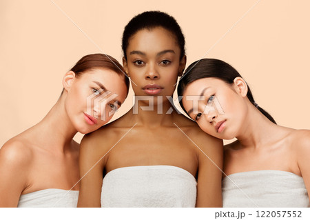 Three Sensual Multicultural Girls Wrapped In Bath Towels Posing Over White Background. Studio Shot Three Sensual Multicultural Girls Wrapped In Bath Towels Posing Over White Background. Studio Shot 122057552
