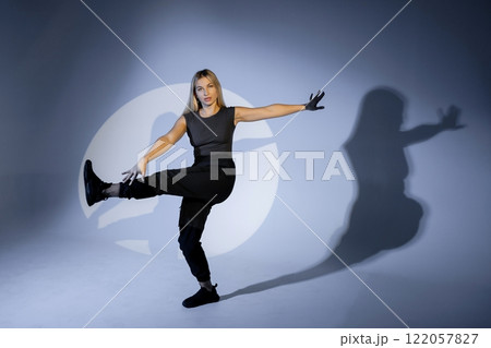 Young dancer performing modern dance illuminated by spotlight in studio Young dancer performing modern dance illuminated by spotlight in studio 122057827