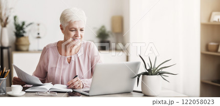 Cheerful senior business woman working with papers at home, checking bills, copy space Cheerful senior business woman working with papers at home, checking bills, copy space 122058023