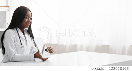 Young black lady doctor consultating patient, client looking at digital tablet screen, copy space 122058168