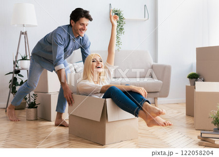 A woman sits in a moving box with her feet up, while her partner smiles at her. A woman sits in a moving box with her feet up, while her partner smiles at her. 122058204