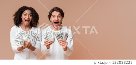 Big Win. Overjoyed interracial couple holding lot of dollar cash and exclaiming with joy, celebrating success together, posing over yellow background 122058225