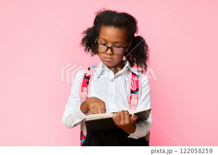 Dyslexia Concept. African Schoolgirl Learning To Read Holding Book Standing In Studio On Over Yellow Background. Dyslexia Concept. African Schoolgirl Learning To Read Holding Book Standing In Studio On Over Yellow Background. 122058259