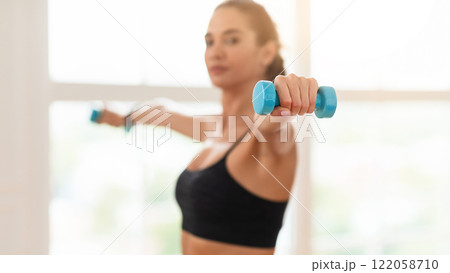 Domestic Training With Weights. Fit woman doing exercises with dumbbells, strengthening her body and arms at home or fitness studio, selective focus on equipment. Female working on her biceps muscles Domestic Training With Weights. Fit woman doing exercises with dumbbells, strengthening her body and arms at home or fitness studio, selective focus on equipment. Female working on her biceps muscles 122058710