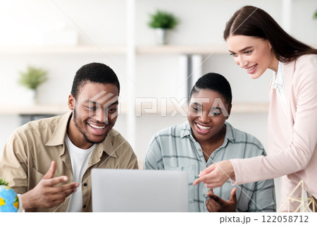 Travel Agency. Female Agent Offering Vacation Tour For Happy African American Couple Pointing At Laptop Recommending Trip Destination In Modern Office. Tourism Services Concept Travel Agency. Female Agent Offering Vacation Tour For Happy African American Couple Pointing At Laptop Recommending Trip Destination In Modern Office. Tourism Services Concept 122058712