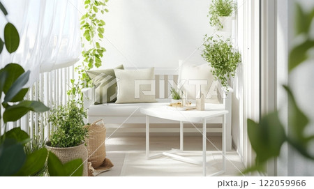 A white balcony with a white bench and white table. There are plants hanging from the ceiling and in pots on the floor. The balcony is decorated with green and white cushions. 122059966