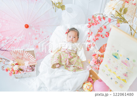初節句のひな祭りで春の桜に囲まれて嬉しそうな赤い袴姿の可愛い女の子赤ちゃん 122061480