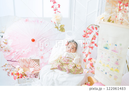 初節句のひな祭りで春の桜に囲まれて嬉しそうな赤い袴姿の可愛い女の子赤ちゃん 122061483