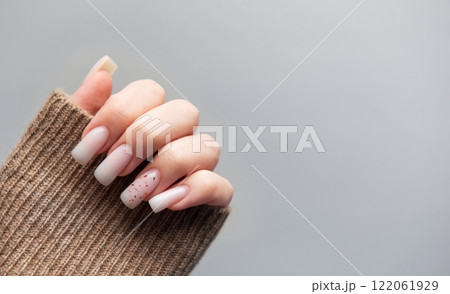 Woman showing stylish pink manicure with brown sleeve on grey background 122061929