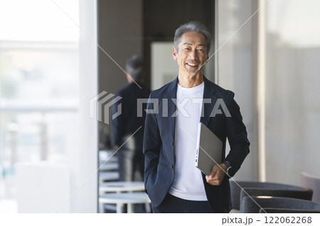ノートパソコンを持ったカメラ目線で笑顔の60代の男性 ノートパソコンを持ったカメラ目線で笑顔の60代の男性 122062268