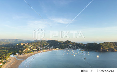 Coastal view of serene bay with boats and lush hills in afternoon light Coastal view of serene bay with boats and lush hills in afternoon light 122062348