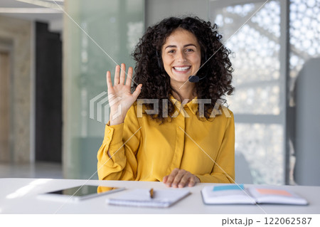 Webcam view, support worker smiling and looking into camera with headset, woman waving hello, helpline customers. 122062587