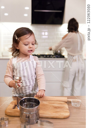 cute little child girl in apron baking cookies in the kitchen cute little child girl in apron baking cookies in the kitchen 122063080
