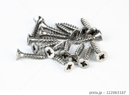 A collection of metal screws scattered on a white background. High quality photo 122063187