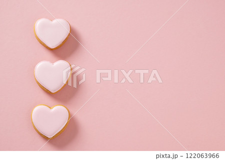 Valentines day greeting card with heart shaped three cookies with pink glaze on girly pastel pink background. View from above. Copy space. Valentines day greeting card with heart shaped three cookies with pink glaze on girly pastel pink background. View from above. Copy space. 122063966