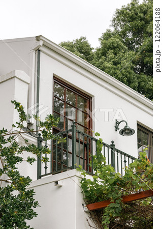 balcony with wrought iron railing, overlooks a lush garden, with green foliage balcony with wrought iron railing, overlooks a lush garden, with green foliage 122064188