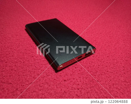 Portable power bank for charging mobile devices on red background Portable power bank for charging mobile devices on red background 122064888