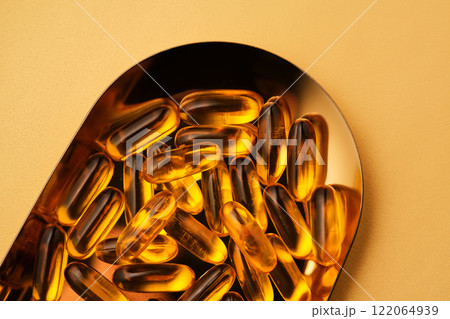 Yellow capsules with Omega-3 fish oil on a golden tray. Yellow capsules with Omega-3 fish oil on a golden tray. 122064939