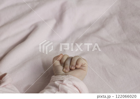 The baby's hand with a little  fingers in pink against white background. Tender fingers of baby girl with copy space 122066020