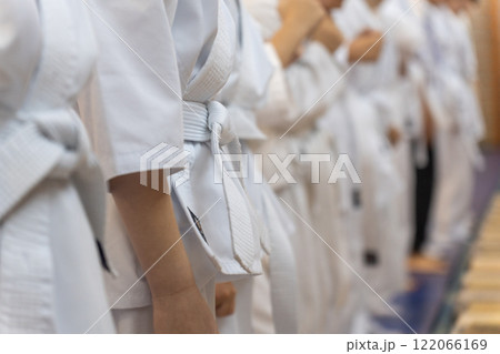 A close-up of a row of young athletes in white karate kimonos with clenched fists. A close-up of a row of young athletes in white karate kimonos with clenched fists. 122066169