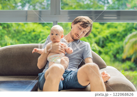 An exhausted father falls asleep on the couch while holding his 3-month-old baby in his arms. A tender and heartwarming moment showcasing love, caregiving, and the challenges of parenthood. Family and An exhausted father falls asleep on the couch while holding his 3-month-old baby in his arms. A tender and heartwarming moment showcasing love, caregiving, and the challenges of parenthood. Family and 122068626