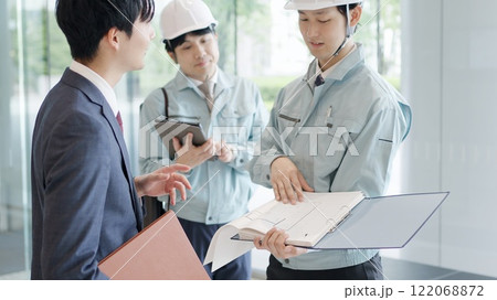 クライアントと打ち合わせをする作業服を着た男性 122068872