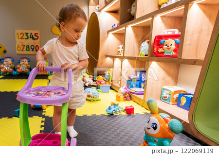 Child exploring playroom with engaging toys and bright design. Concept of fun and educational play indoors 122069119