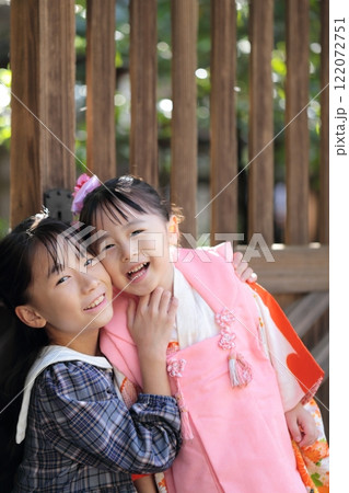 神社に七五三の参拝をする3歳の女の子と姉 122072751
