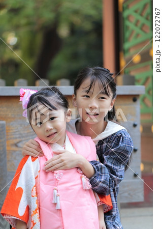 神社に七五三の参拝をする3歳の女の子と姉 122072767