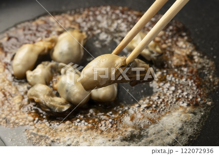鉄板で焼いた牡蠣を皿に盛り付ける 鉄板で焼いた牡蠣を皿に盛り付ける 122072936