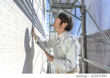 戸建て家屋の外壁修繕工事進行状況を確認する男性 戸建て家屋の外壁修繕工事進行状況を確認する男性 122072947