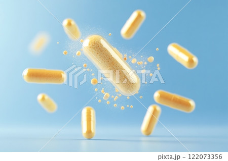Yellow capsule disintegrating and releasing granules on light blue background 122073356