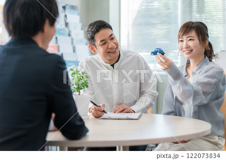 ショールーム・商談スペースで話を聞く夫婦と接客するビジネスマン 122073834
