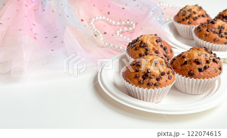 Chocolate chip muffins on plates with pastel tulle and beads background. Birthday concept 122074615