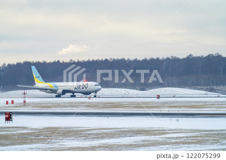 冬の新千歳空港　雪煙と離陸する飛行機　北海道千歳市　 122075299