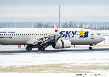 冬の新千歳空港　雪煙と着陸する飛行機　北海道千歳市　 122075399