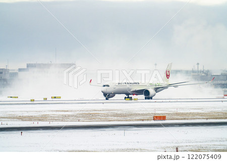 冬の新千歳空港　雪煙とタキシング中の飛行機　北海道千歳市　 122075409