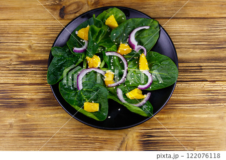 Tasty salad with spinach, orange, red onion and sesame seeds on wooden table. Top view. Healthy food or vegetarian concept Tasty salad with spinach, orange, red onion and sesame seeds on wooden table. Top view. Healthy food or vegetarian concept 122076118