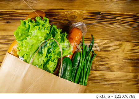 Paper bag with different food on wooden table. Top view. Grocery shopping concept 122076769