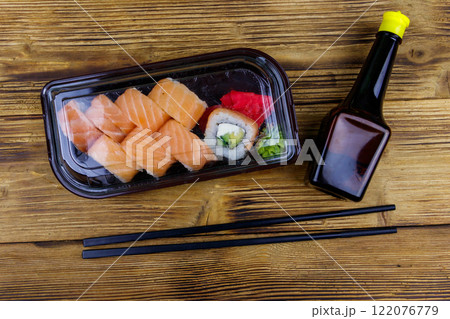 Sushi rolls Philadelphia in plastic box on wooden table. Top view. Sushi for take away or delivery of sushi in plastic container 122076779