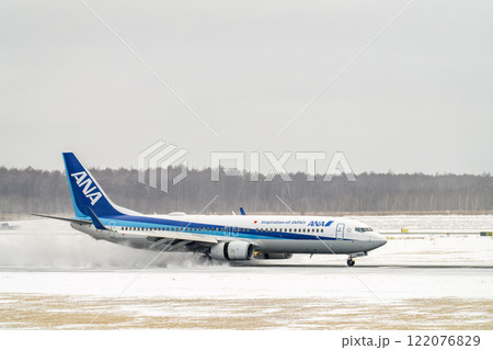 冬の新千歳空港　雪煙と着陸する飛行機　北海道千歳市　 122076829