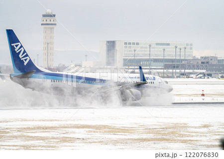 冬の新千歳空港　雪煙と着陸する飛行機　北海道千歳市　 122076830