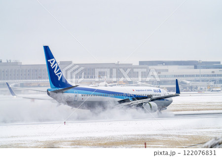 冬の新千歳空港　雪煙と着陸する飛行機　北海道千歳市　 122076831