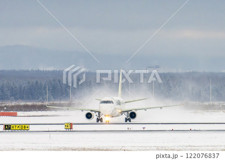 冬の新千歳空港　雪煙とタキシング中の飛行機　北海道千歳市　 122076837