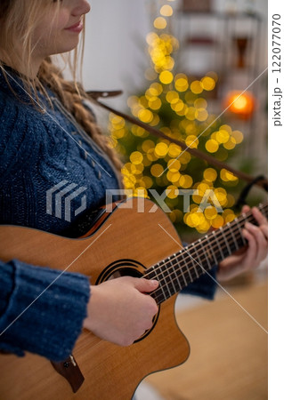 A Cozy Holiday Music Scene Featuring a Guitar Amidst Beautifully Lit Christmas Lights A Cozy Holiday Music Scene Featuring a Guitar Amidst Beautifully Lit Christmas Lights 122077070