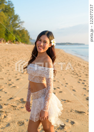 Golden Hour Beauty Asian Woman Enjoying Peaceful Sunset at the Beach 122077237