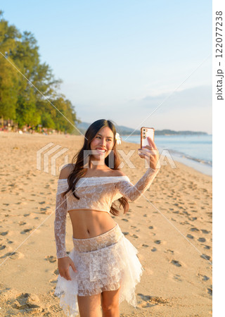 Young Thai Woman Vlogging on Smartphone at a Tropical Beach During Sunset Young Thai Woman Vlogging on Smartphone at a Tropical Beach During Sunset 122077238
