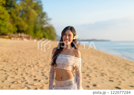 Golden Hour Beauty Asian Woman Enjoying Peaceful Sunset at the Beach 122077284